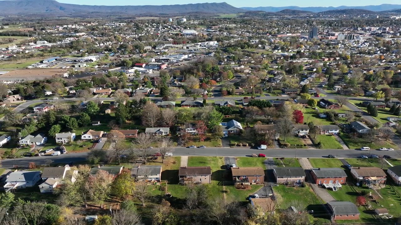 Luce solare in un'area residenziale americana con case di lusso negli Stati Uniti. Zona tranquilla nella periferia di una piccola città. Alberi colorati lungo una strada dritta con vialetti d'accesso. Ampia ripresa aerea laterale