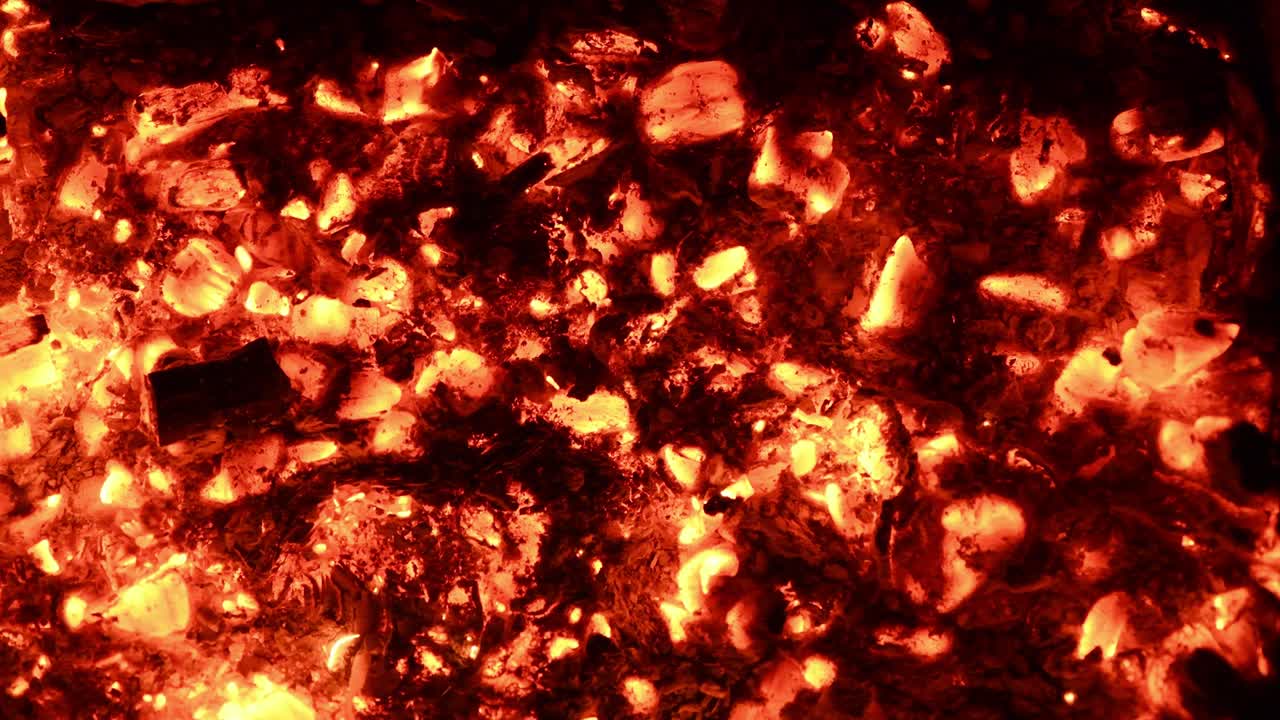 Smoldering coals of a fire in a strong wind. Sparks fly out. Top view.