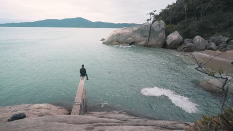 Young-man-sitting-relaxing-on-a-trampoline-above-the-water-on-a-secret-brazilian-beach