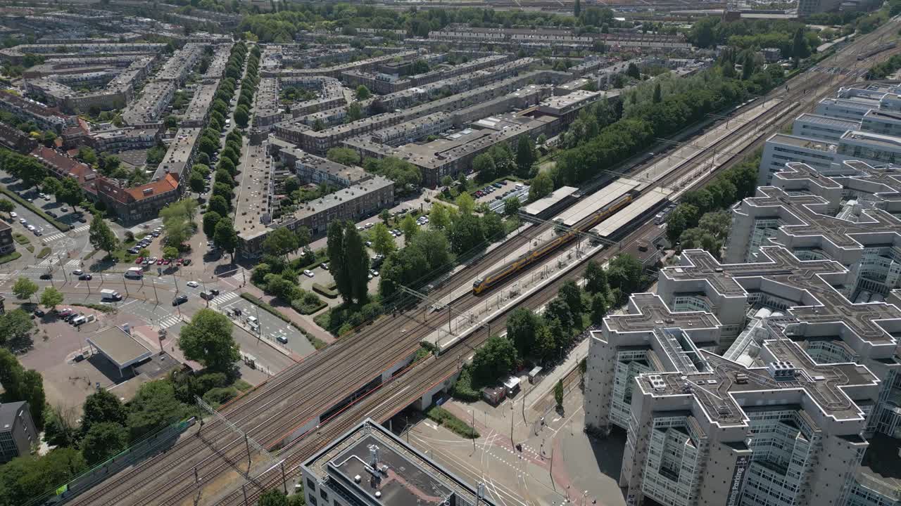A top-down view of a modern urban area with trams, roadways, and residential housing in The Hague.