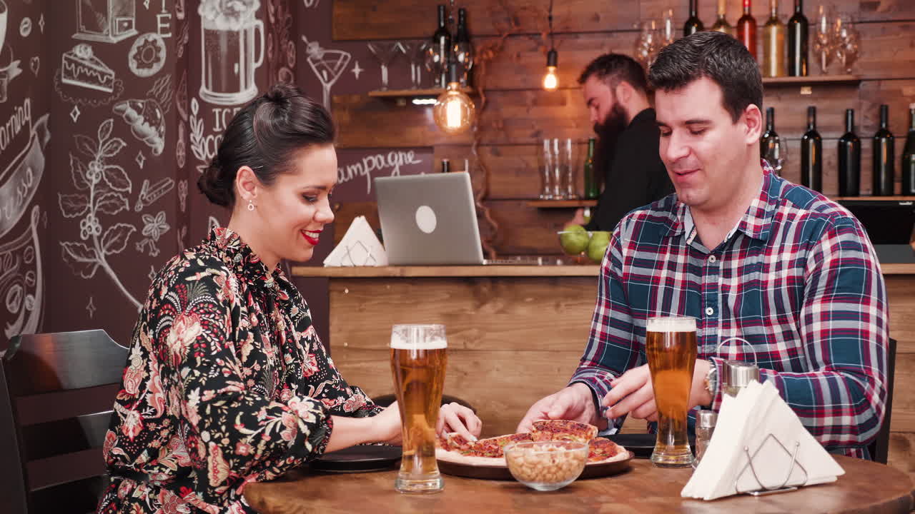Couple enjoying beer and pizza at a restaurant
