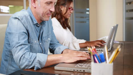 un hombre de negocios casual sonriente escribiendo en una computadora portátil