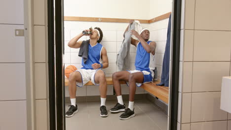 resting in locker room, basketball players discussing strategy, holding water bottles