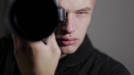 un fotógrafo masculino tomando una foto frente a la cámara en el estudio - plano medio