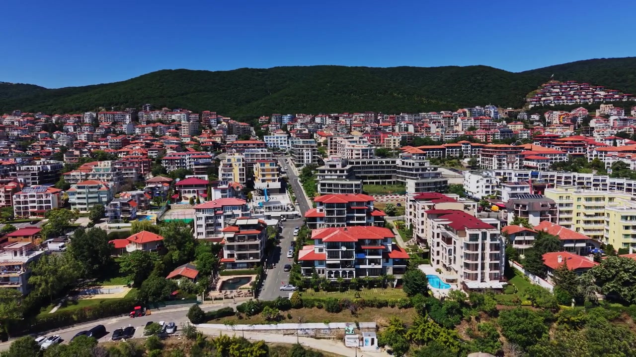 Güneşli bir konumda binalar ve havuzlarla dolu bir yerleşim alanı manzarası.