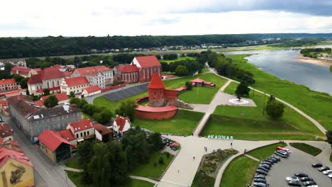 drone shot of the historic old red brick kaunas castle with vytis statue and ukrainian flagnear nemunas river in kaunas old town, lithuania on a sunny day, parallax shot