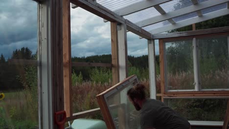 man installing the glass window with wooden frame