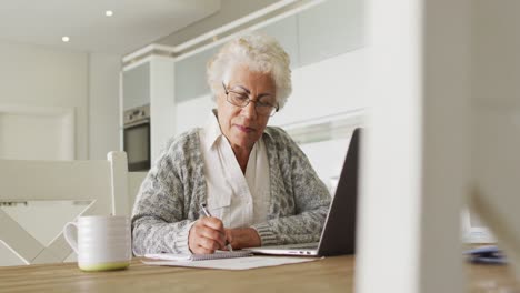 African-american-senior-woman-with-laptop-taking-notes-at-home