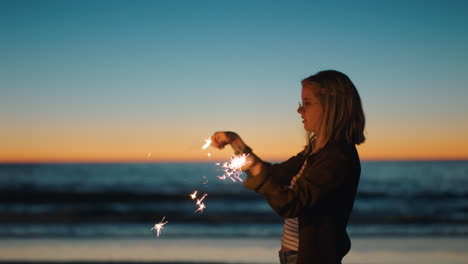 mujer bailando con bengalas en la playa al atardecer celebrando la víspera de año nuevo niña divirtiéndose bailando con fuegos artificiales disfrutando de la celebración del día de la independencia junto al mar