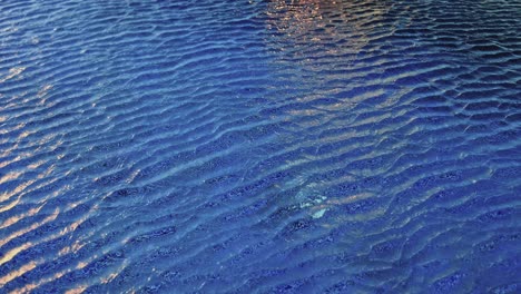 swimming pool surface with waves and ripples caused by wind
