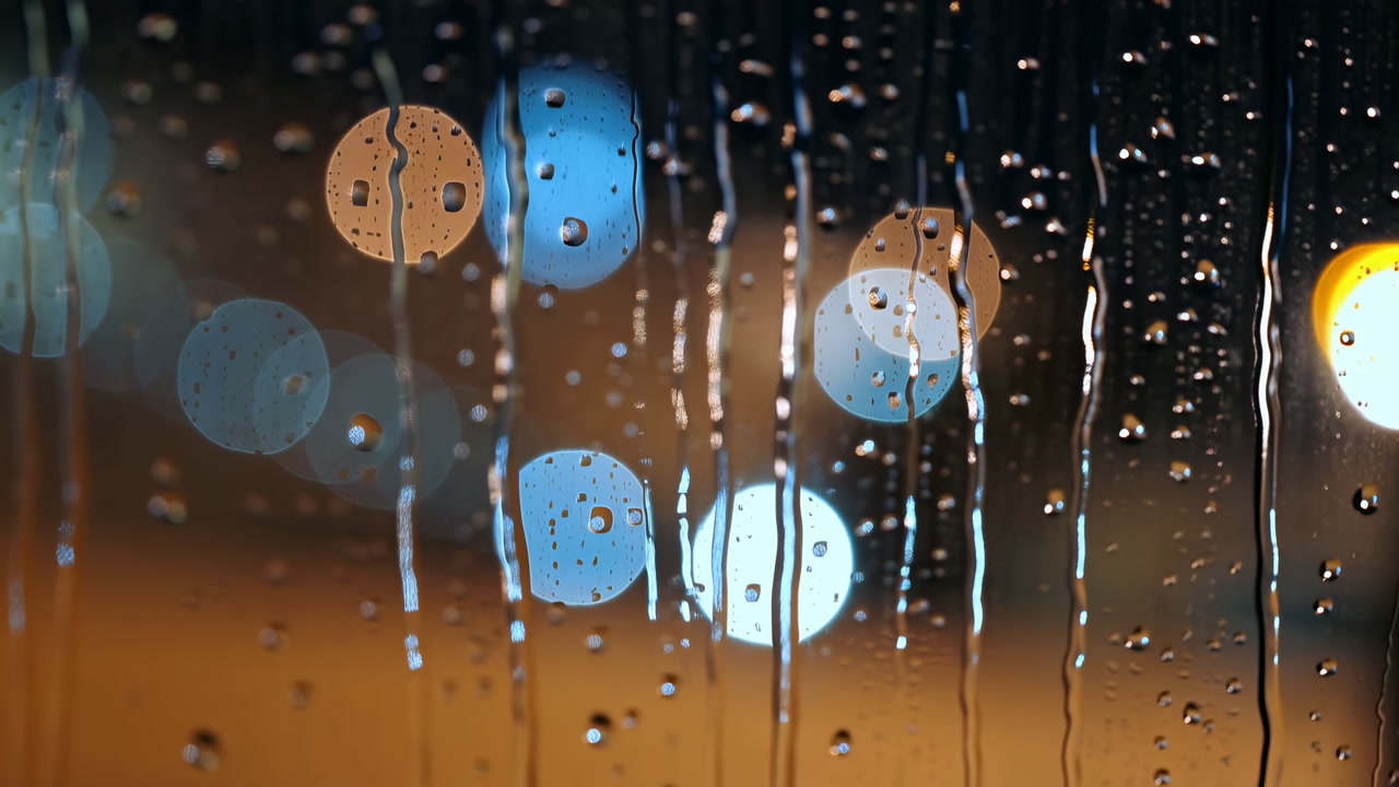 Raindrops Falling on Glass with City Lights Bokeh at Night