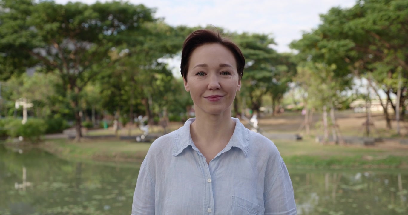 緑豊かな公園でポーズをとるショートヘアの笑顔の女性