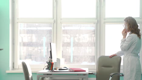 female doctor talking on phone and sitting on office chair in her consulting room