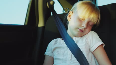 blonde girl 6 years dozing in the back seat of the car traveling in a car with children 4k video