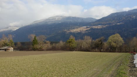 agricultural field in spring with snow-dusted hills in the background.