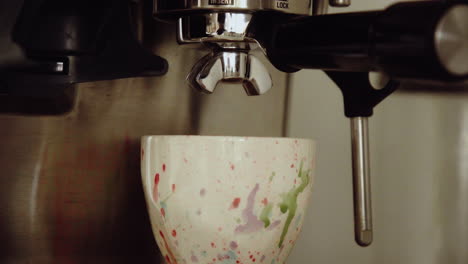 Mounting-the-portafilter-with-coffee-ground-in-espresso-machine-and-placing-beautiful-cup-under-it