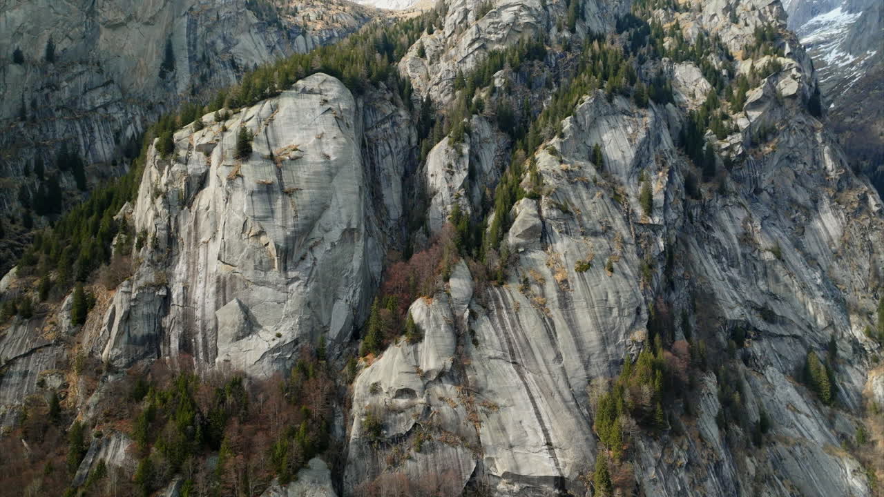 vista aérea de una montaña escarpada y rocas cubiertas de pinos en el valle de mello, italia