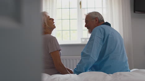 Una-Pareja-De-Ancianos-Jubilados-Preocupados-Sentados-En-La-Cama-En-Casa-Hablando-Juntos