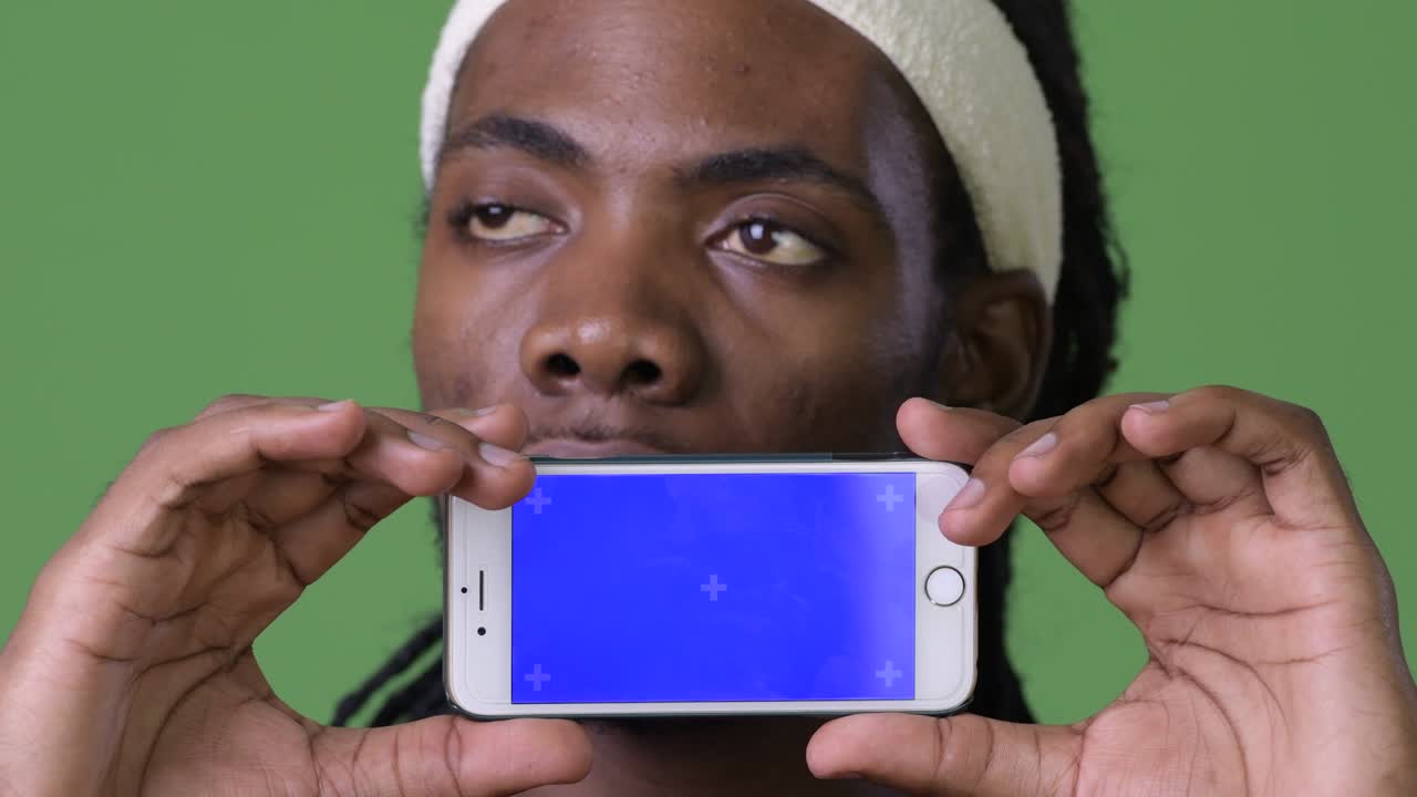 Young handsome African man with dreadlocks against green background