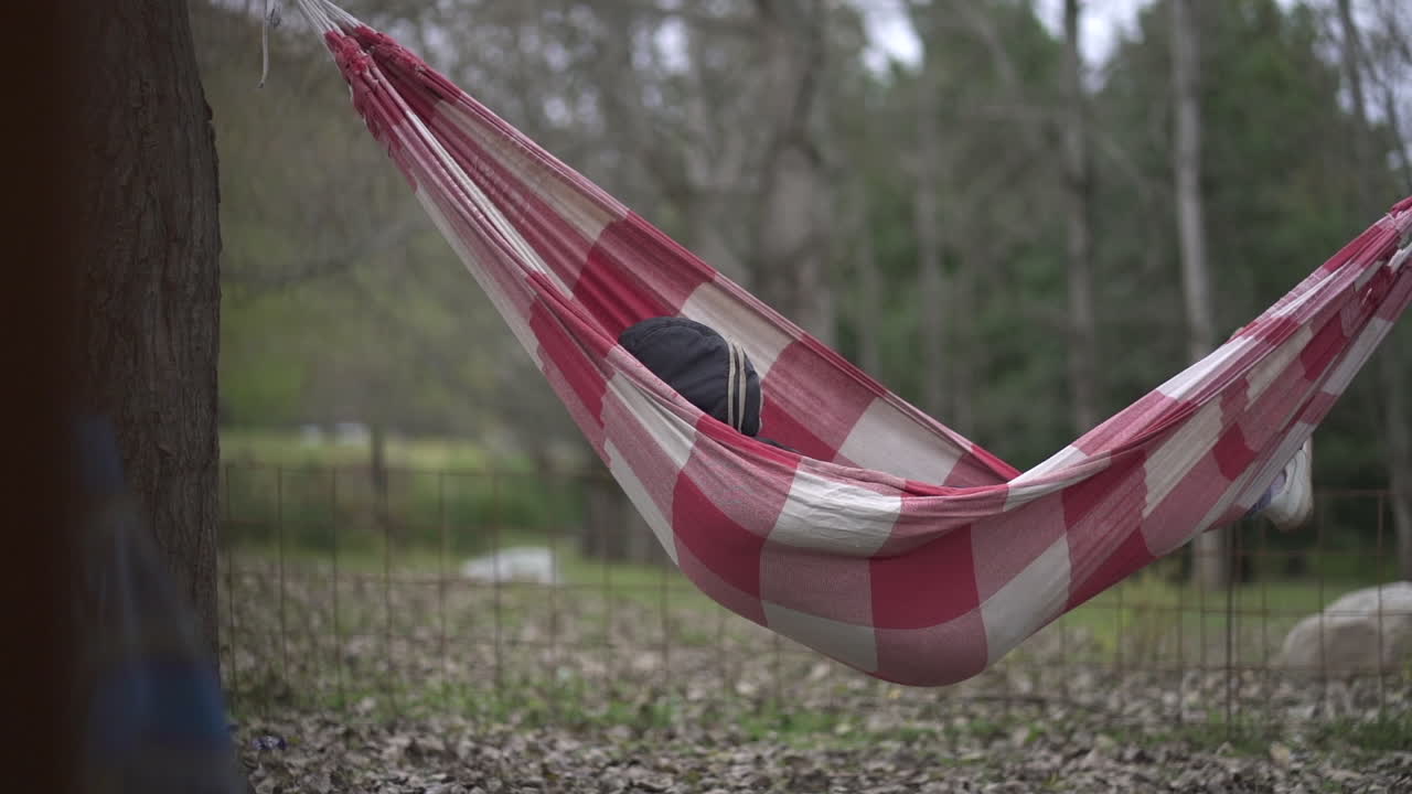 una persona con una capucha descansando pacíficamente en una hamaca en medio de un bosque