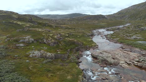 meltwater river flowing in norway hardangervidda valley, aerial side truck view