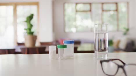 cerrar las cajas de pastillas y un vaso de agua con vasos en la mesa en la sala de estar