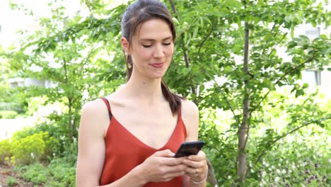 una joven alemana de cabello largo y marrón está escribiendo en su teléfono inteligente o móvil