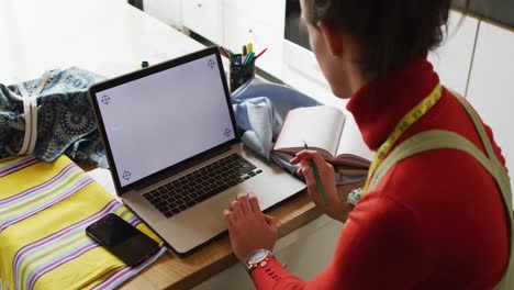 Caucasian-non-binary-transgender-woman-working-at-home,-using-laptop-with-copy-space