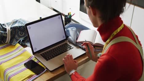mujer transgénero caucásica no binaria que trabaja en casa, usando una computadora portátil con espacio para copiar