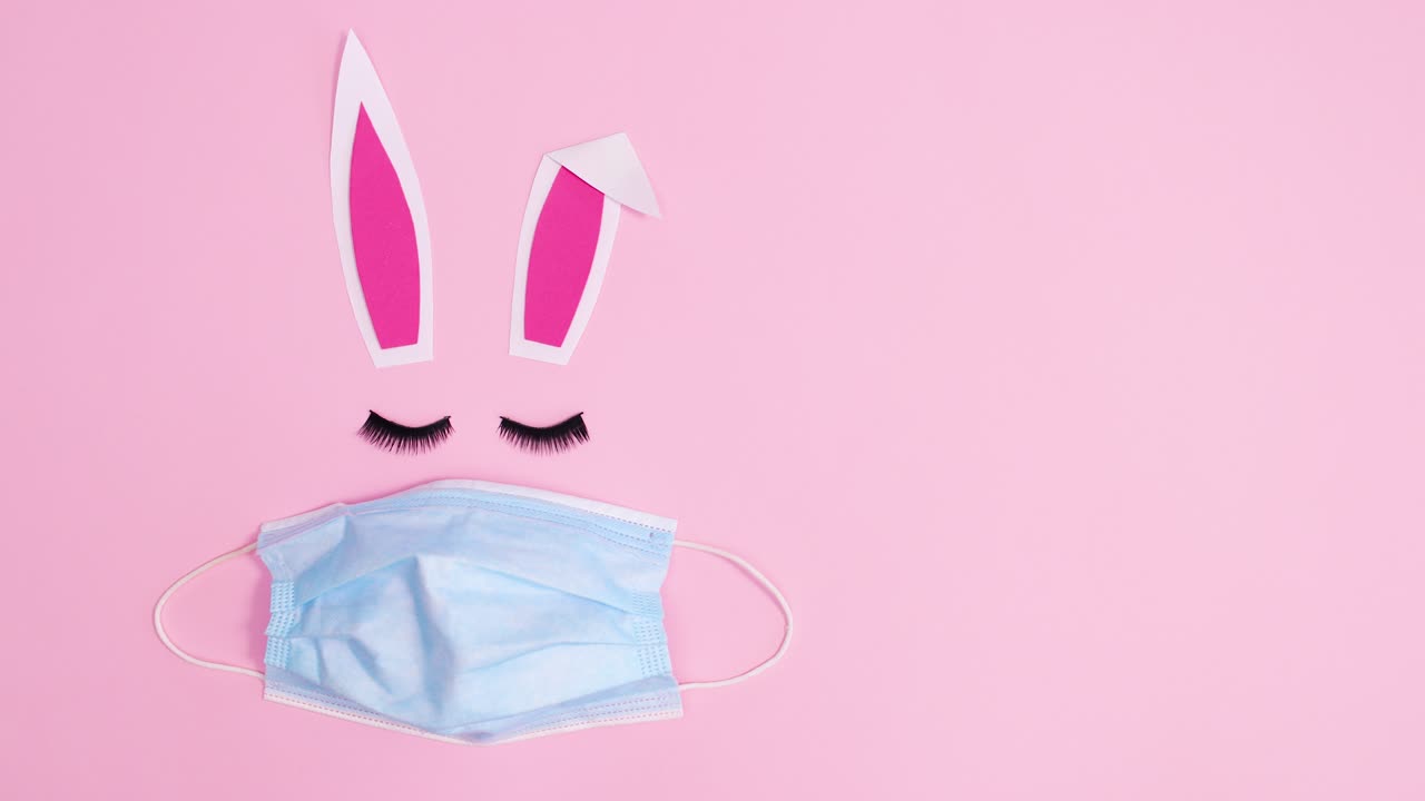 Creative Easter bunny with face mask blinking with eye lashes. Stop motion flat lay