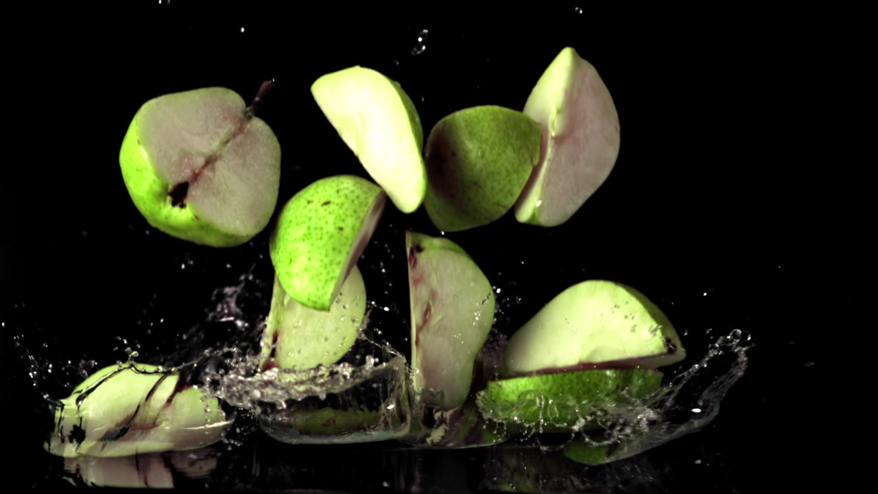 Fette di pera verde che cadono e schizzano nell'acqua.