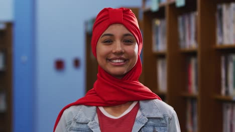 portrait of a smiling asian female student wearing a red hijab and looking at camera