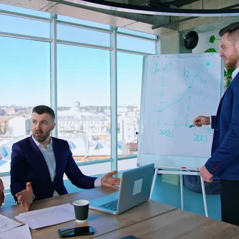 young manager talking to his coworkers near the board. team of business people in modern office with a city view window. entrepreneurs work together