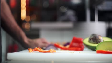 cinematic and slow motion view of a hand smashing and crushing a red bell pepper in a fine restaurant cuisine.
