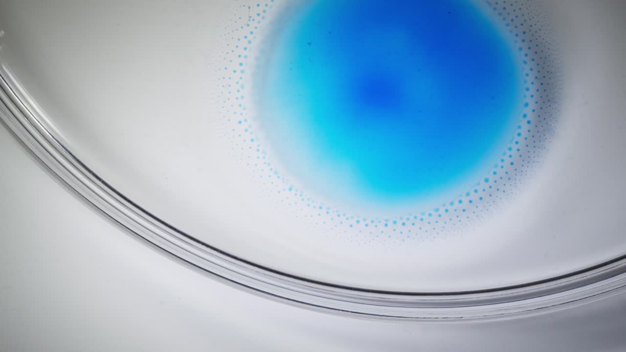 Abstract macro ink pattern in motion, calming blue spread in white dish fluid art