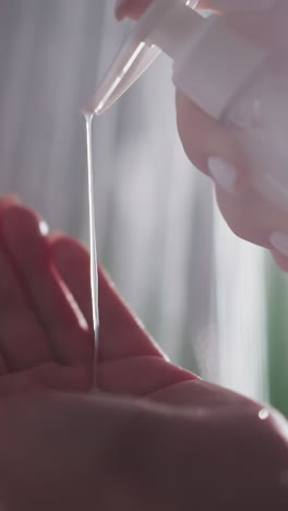 woman pours liquid soap on palm in bathroom closeup. lady takes cream gel from dispenser bottle in shower cabin. body wash cosmetic product