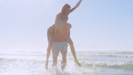 Hombre-Dando-Mujer-A-Cuestas-En-Vacaciones-De-Verano-En-La-Playa