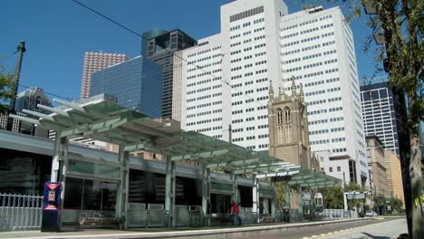 a rapid transit train moves quickly through downtown houston with fountains dancing