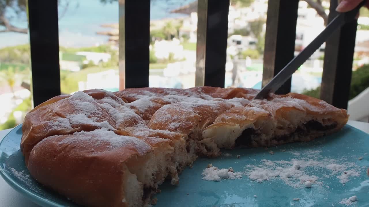 Chocolate-filled ensaimada, freshly cut, with powdered sugar topping