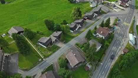 aerial view of a car driving on any empty street in a quiet neighborhood, lined with family homes on a field of lush green grass and trees