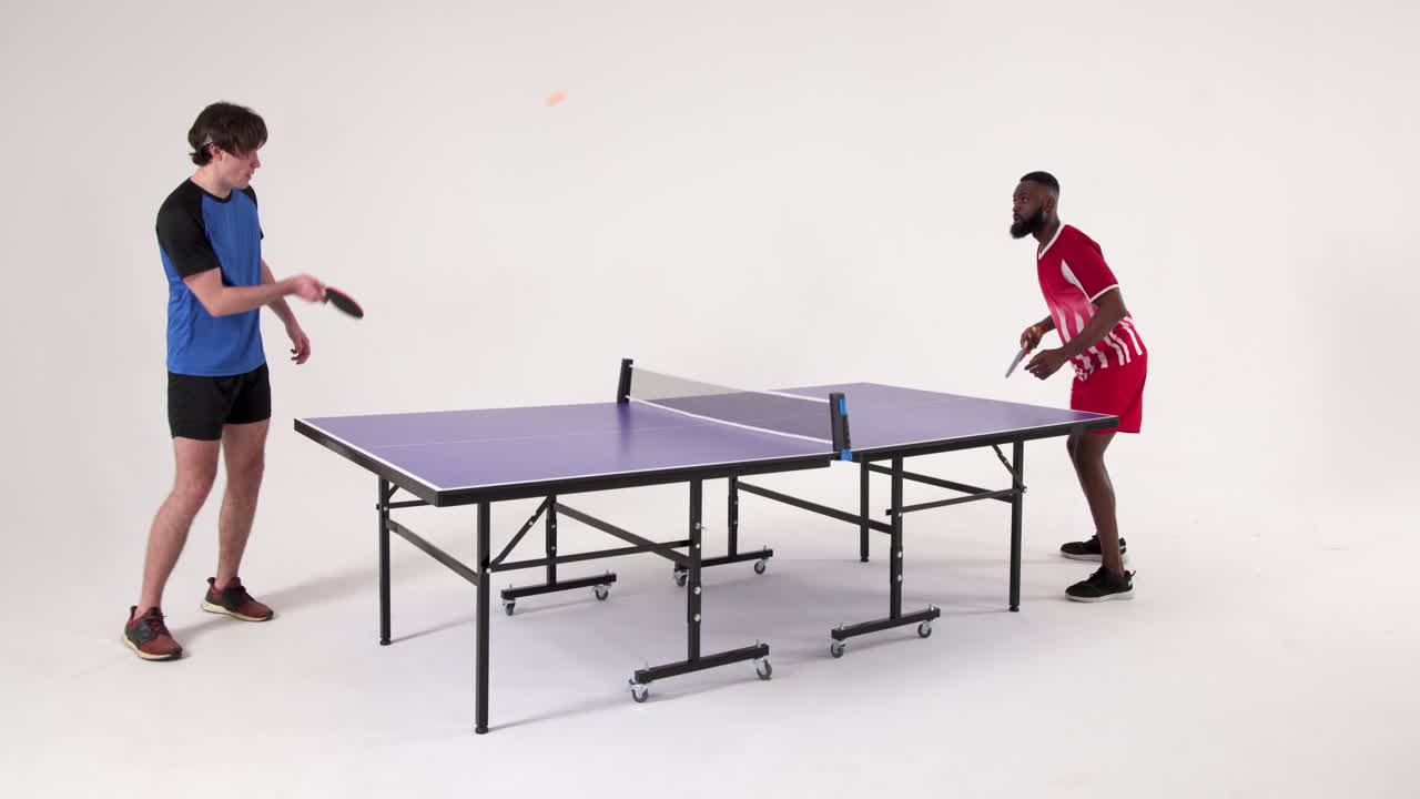 Playing table tennis, two men competing in friendly match indoors