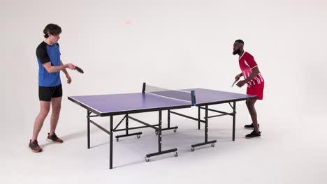 playing table tennis, two men competing in friendly match indoors