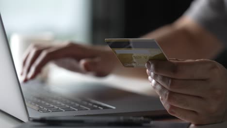 mãos masculinas segurando cartão de crédito e usando laptop. compras on-line