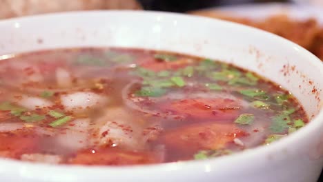 a close-up view of a colorful soup garnished with fresh herbs in a white bowl.