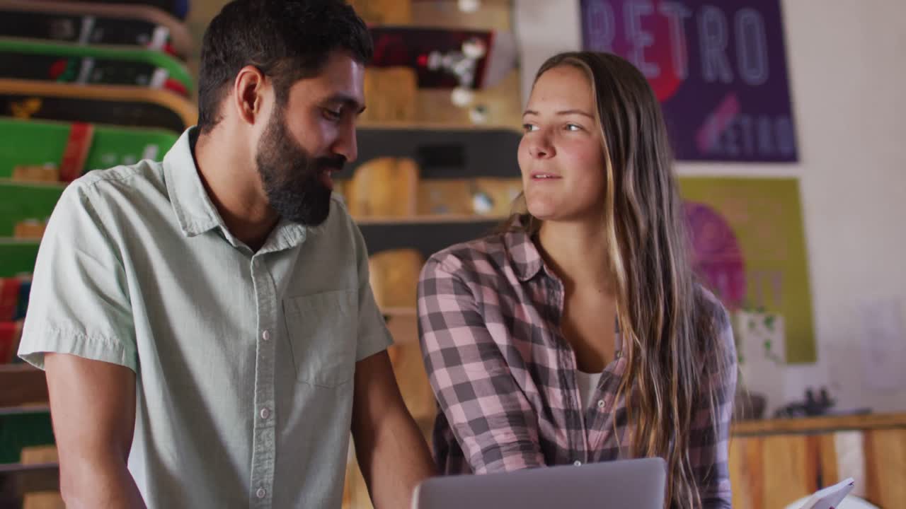 video de diversas patinadoras y patinadores usando una computadora portátil en una tienda de patinaje