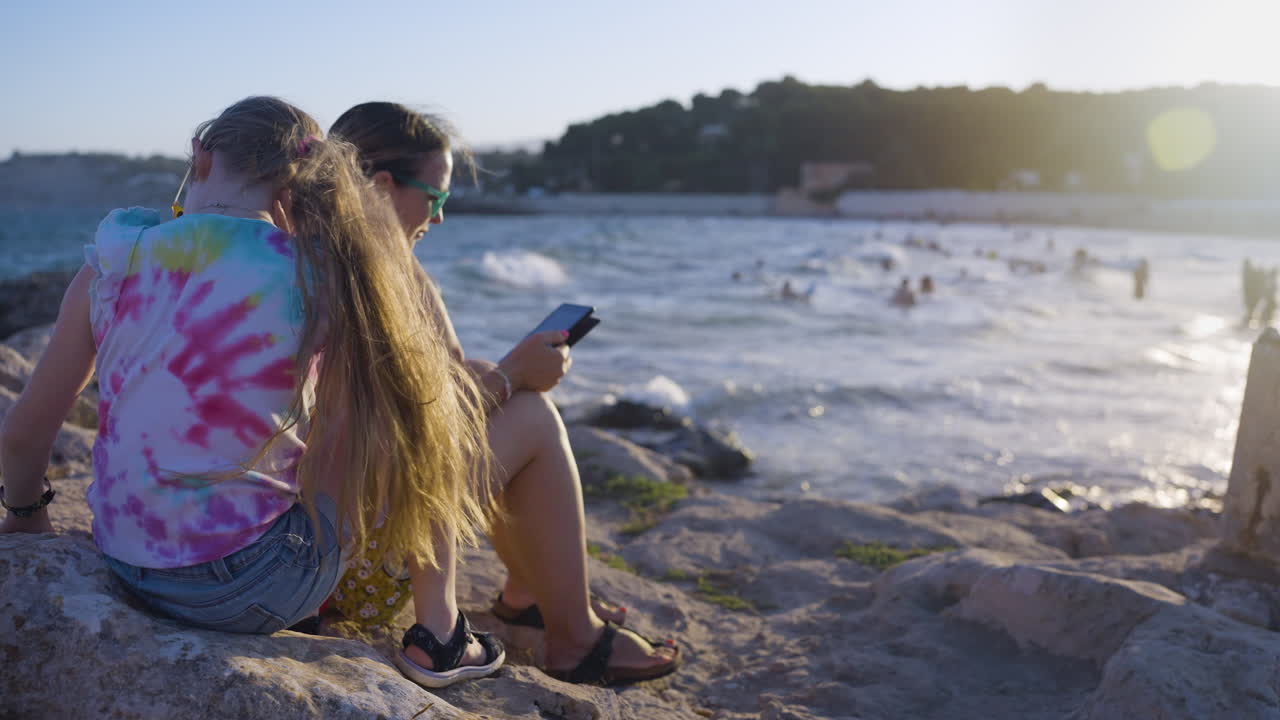 Mother and daughter relaxing on the beach at sunset