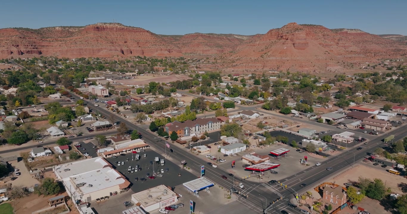 Strade e case a Kanab, Utah, sotto formazioni di mesa rosse del deserto, sfondo aereo da drone
