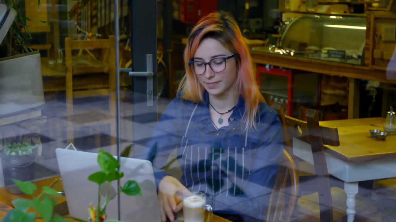 Female owner having cold coffee while working on laptop 4k