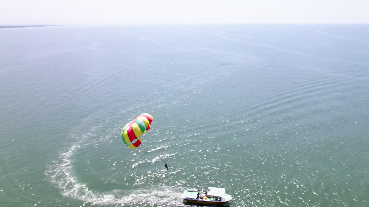 Tourist riding speed boat Parasailing on Arabian Sea in background colva beach at south goa, india. day time, circle shot, drone shot, 4k