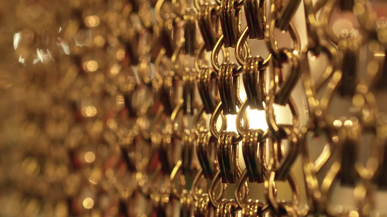 긴 금 사슬의 느리고 부드러운 움직임, 균일한 스, 휴식을 위한 금색 배경, 명상, 휴식, 진정시키기 위한 질감, 반이는 빛, 수직 그림, 흐릿한 그림.